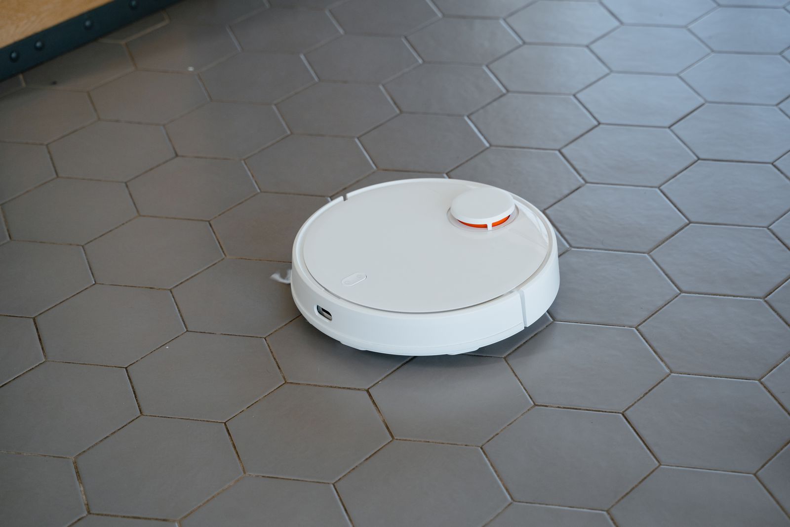 Robotstøvsuger med moppefunksjon vasker et lyst flisgulv